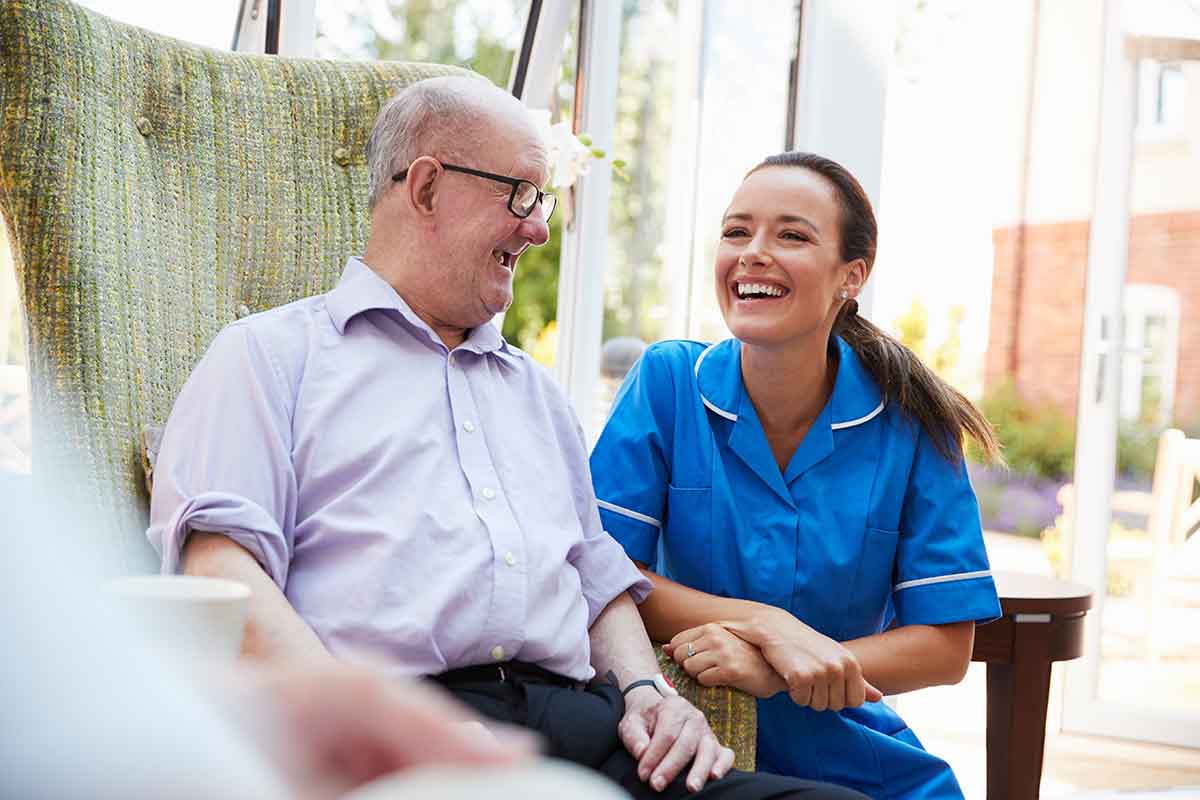 Dominion of Frankfort | Senior man in chair talking with nurse in retirement home