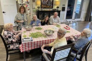 Dominion of Richmond | Seniors sitting at a table and breaking beans and smiling