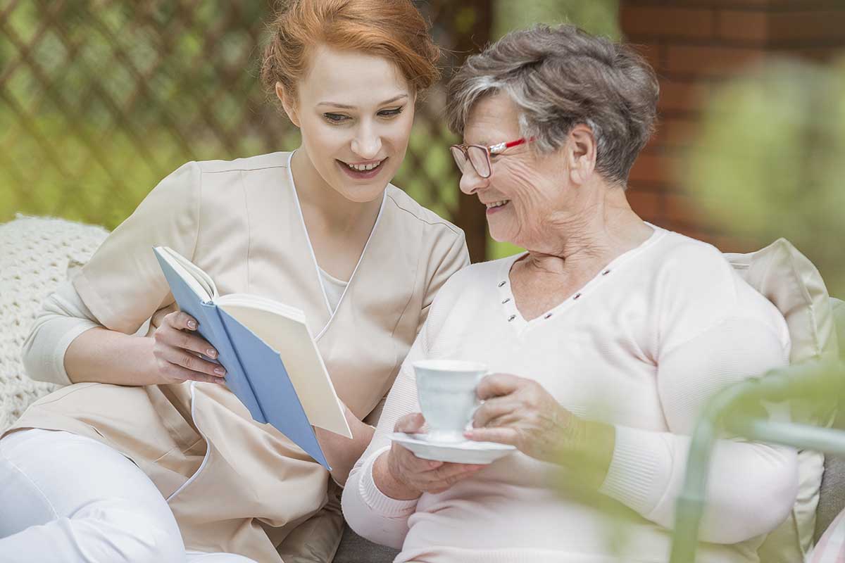 Dominion of Johnson City | Redhead nurse shows photo album to senior lady