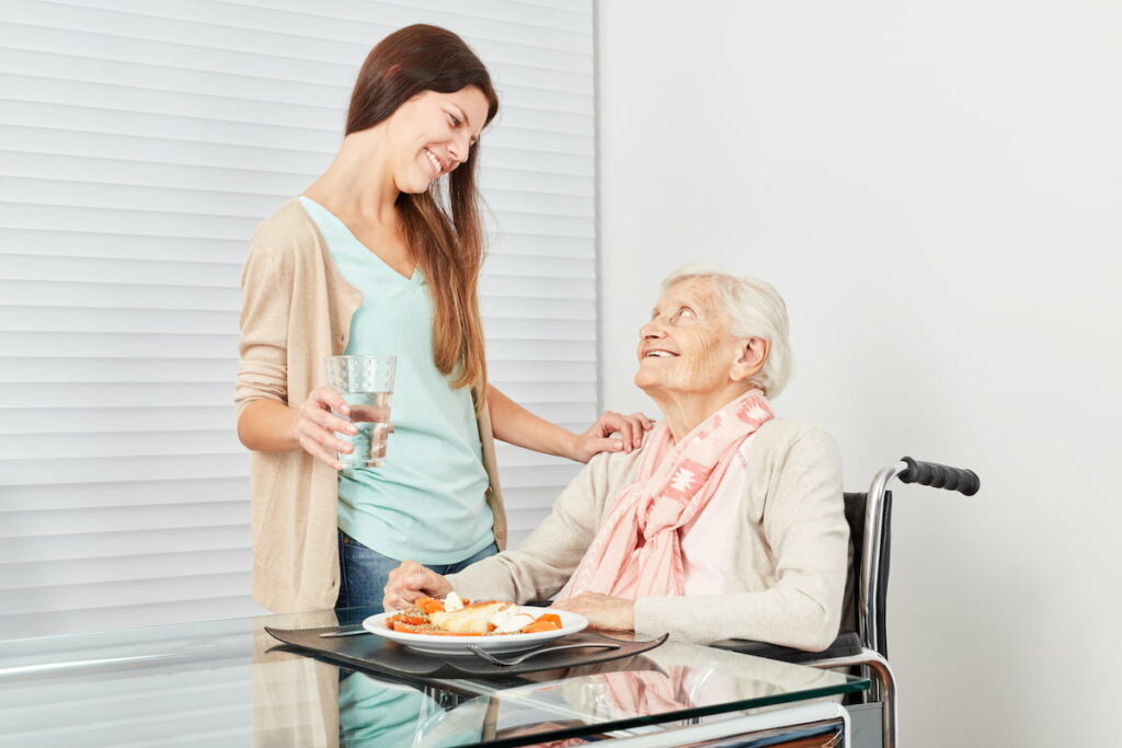 Dominion of Richmond | Smiling senior woman with caregiver eating breakfast