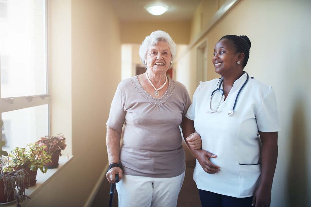 Dominion of Louisville | Smiling senior woman walking down the community hallway with her caregiver
